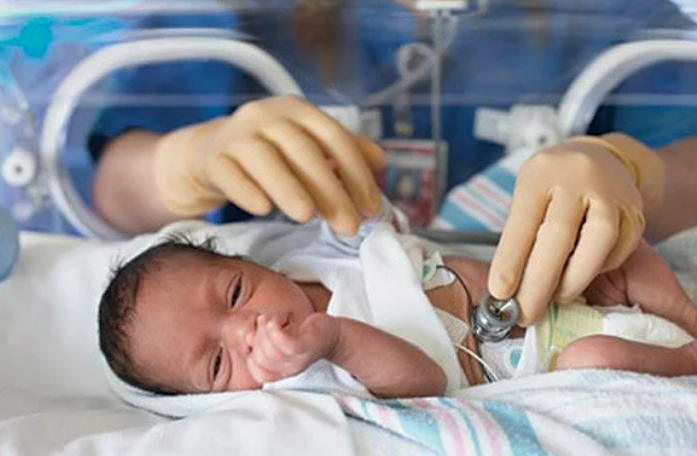 Pediatrician providing NICU follow-up care to infant with mother present