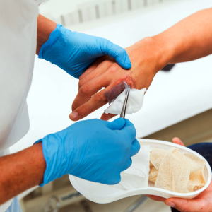 A healthcare professional providing wound care treatment to a patient using sterile techniques.